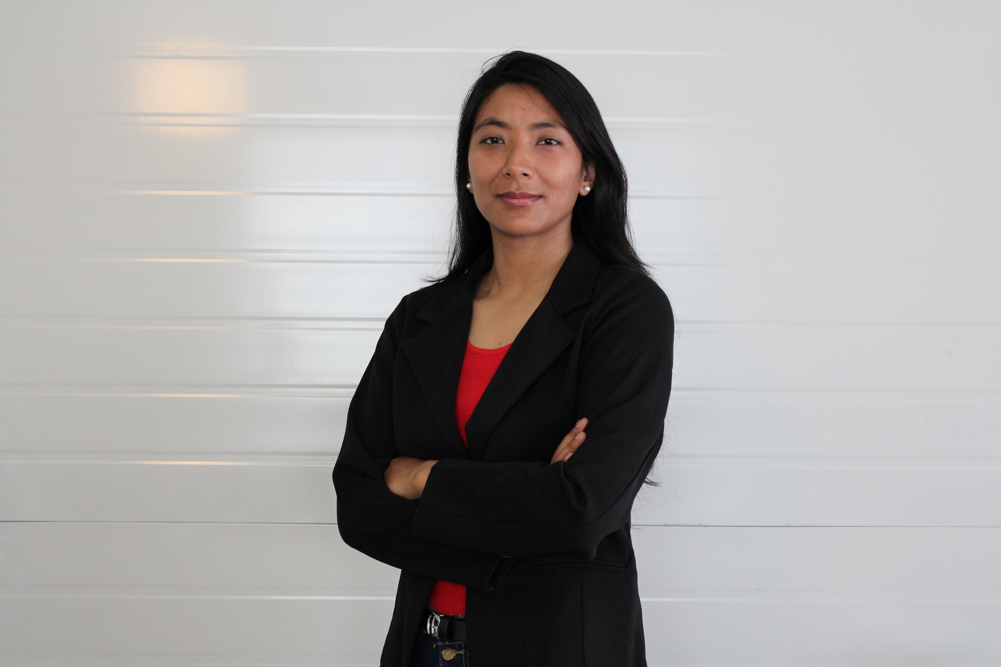https://media.devpulse.info/A female wearing red vest and black coat standing with her arms crossed posing for the camera.